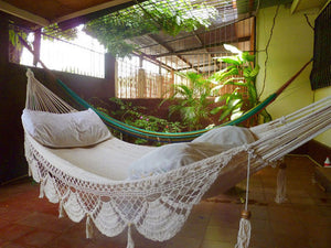 Bondi white hammock with fringe side view hanging in an outdoor area