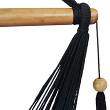 Detail view of end of black hammock chair wooden bar and tassel
